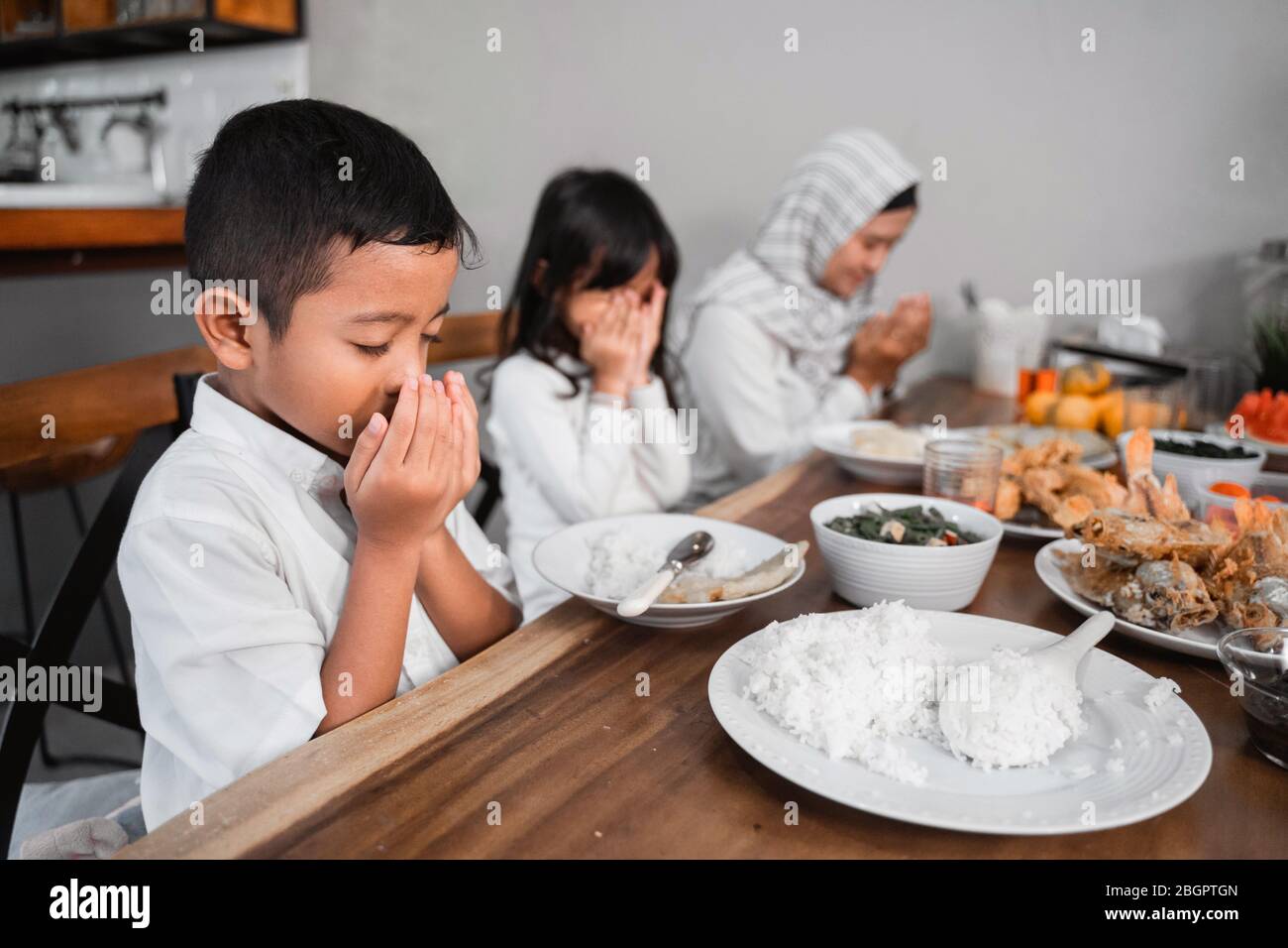 famiglia musulmana che prega prima di mangiare il loro cibo. rompere il veloce o iftar cena Foto Stock