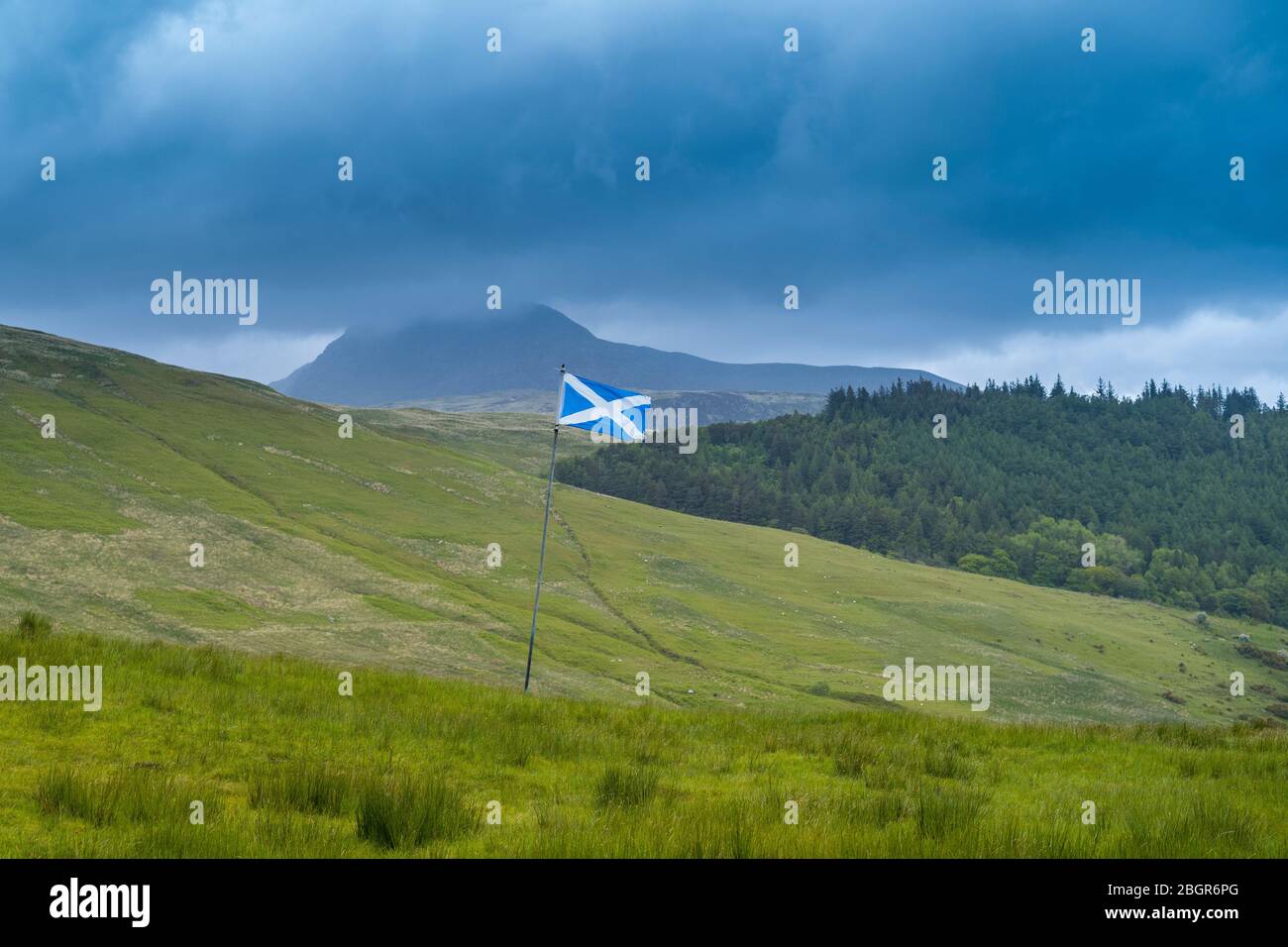 La bandiera di Scozia, chiamata il abbigliamento di salvataggio o croce di Sant'Andrea, volando da una bandiera in tipico paesaggio scozzese, l'isola di Arran Foto Stock