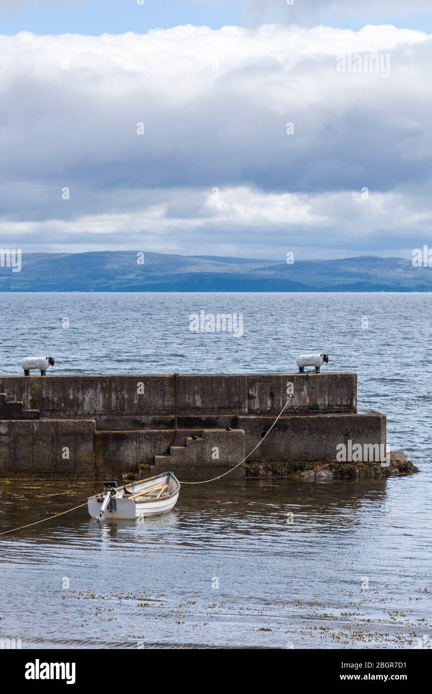 Barca a remi ormeggiata a un bollo a forma di pecora sul muro di mare nel porto vicino a Corrie sull'isola di Arran, Scozia Foto Stock