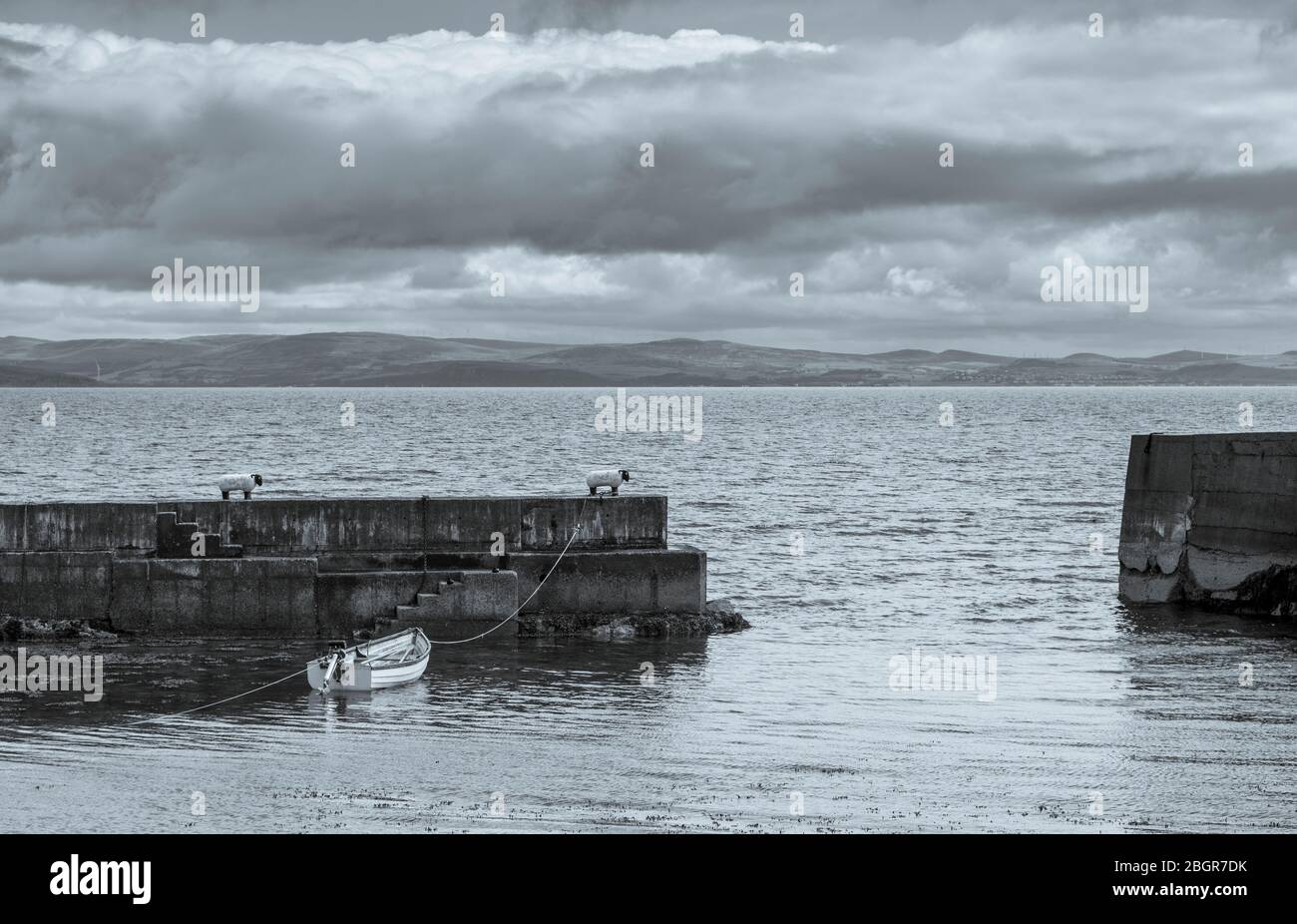 Barca a remi ormeggiata a un bollo a forma di pecora sul muro di mare nel porto vicino a Corrie sull'isola di Arran, Scozia Foto Stock