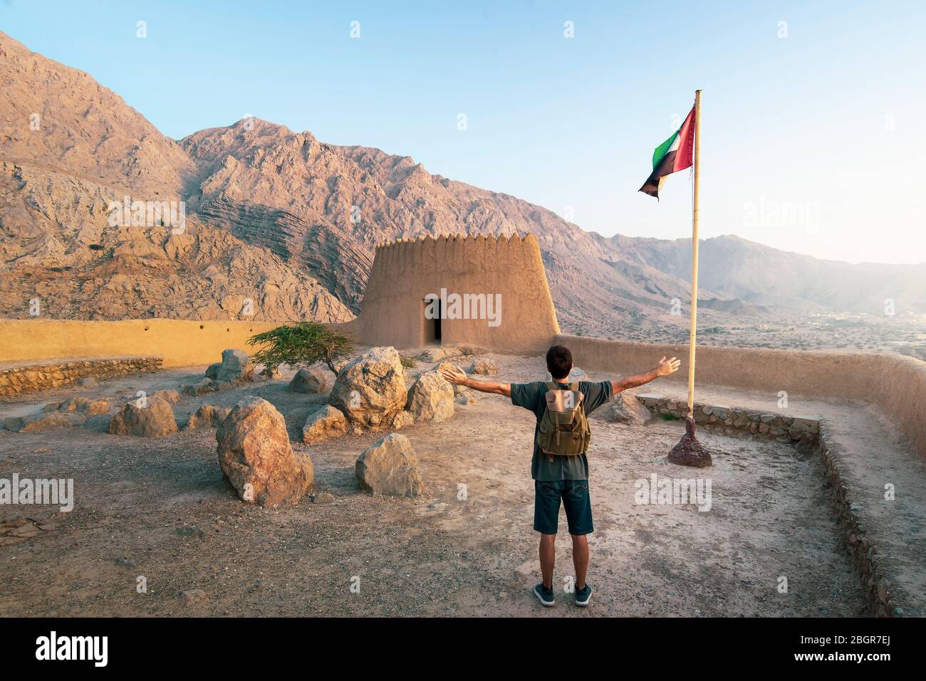 Il viaggiatore che esplora il Forte di Dhayah nel nord di Ras al Khaimah Emirati Arabi Uniti e gode di una vista al tramonto Foto Stock