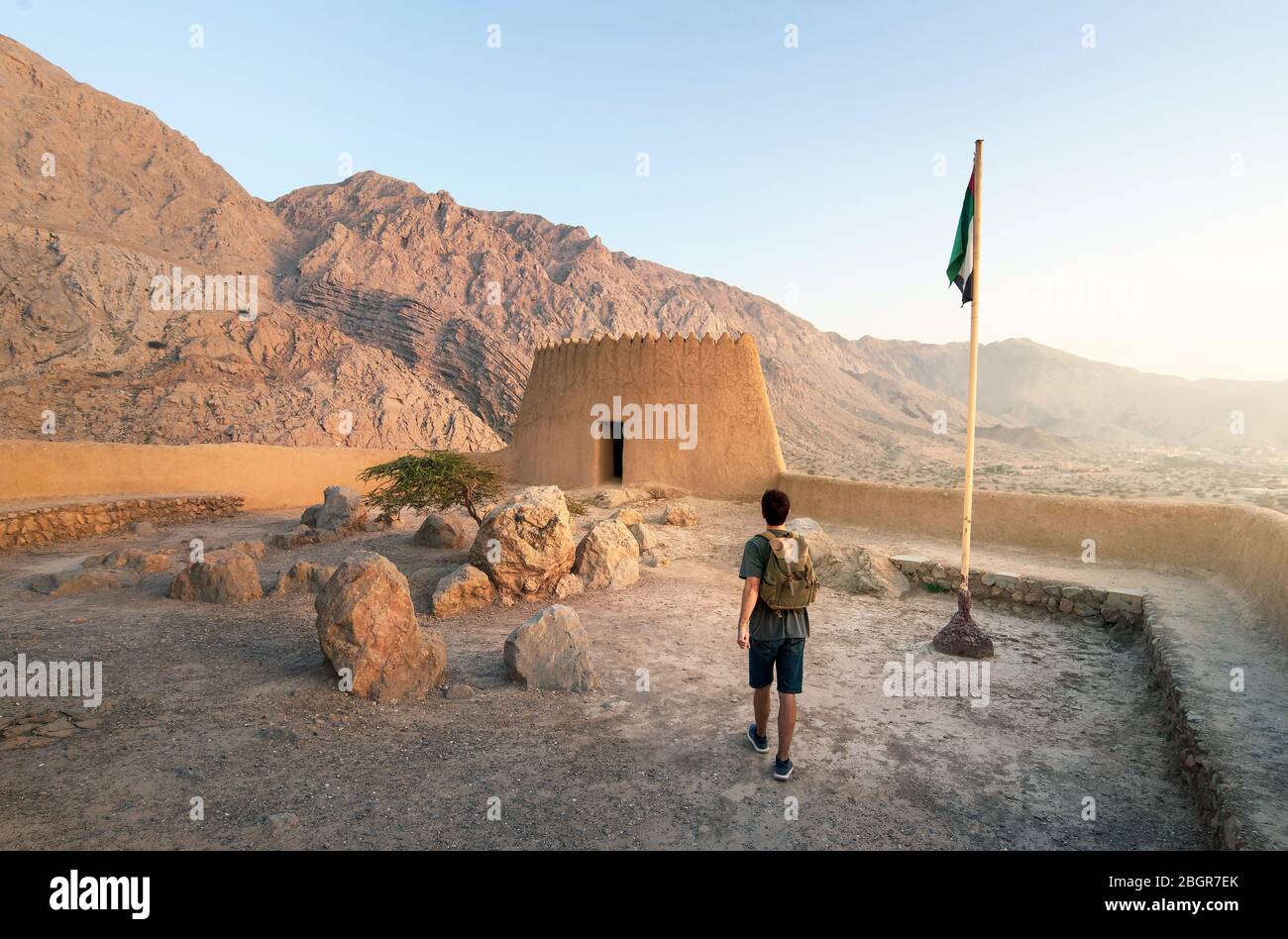 Il viaggiatore che esplora il Forte di Dhayah nel nord di Ras al Khaimah Emirati Arabi Uniti e gode di una vista al tramonto Foto Stock
