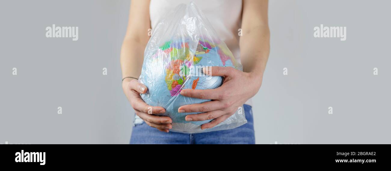 la ragazza tiene un globo terrestre in una borsa di plastica. concetto senza plastica, eco-compatibile, stile di vita zero rifiuti, consumo consapevole delle risorse. ecologia pianeta. Foto Stock