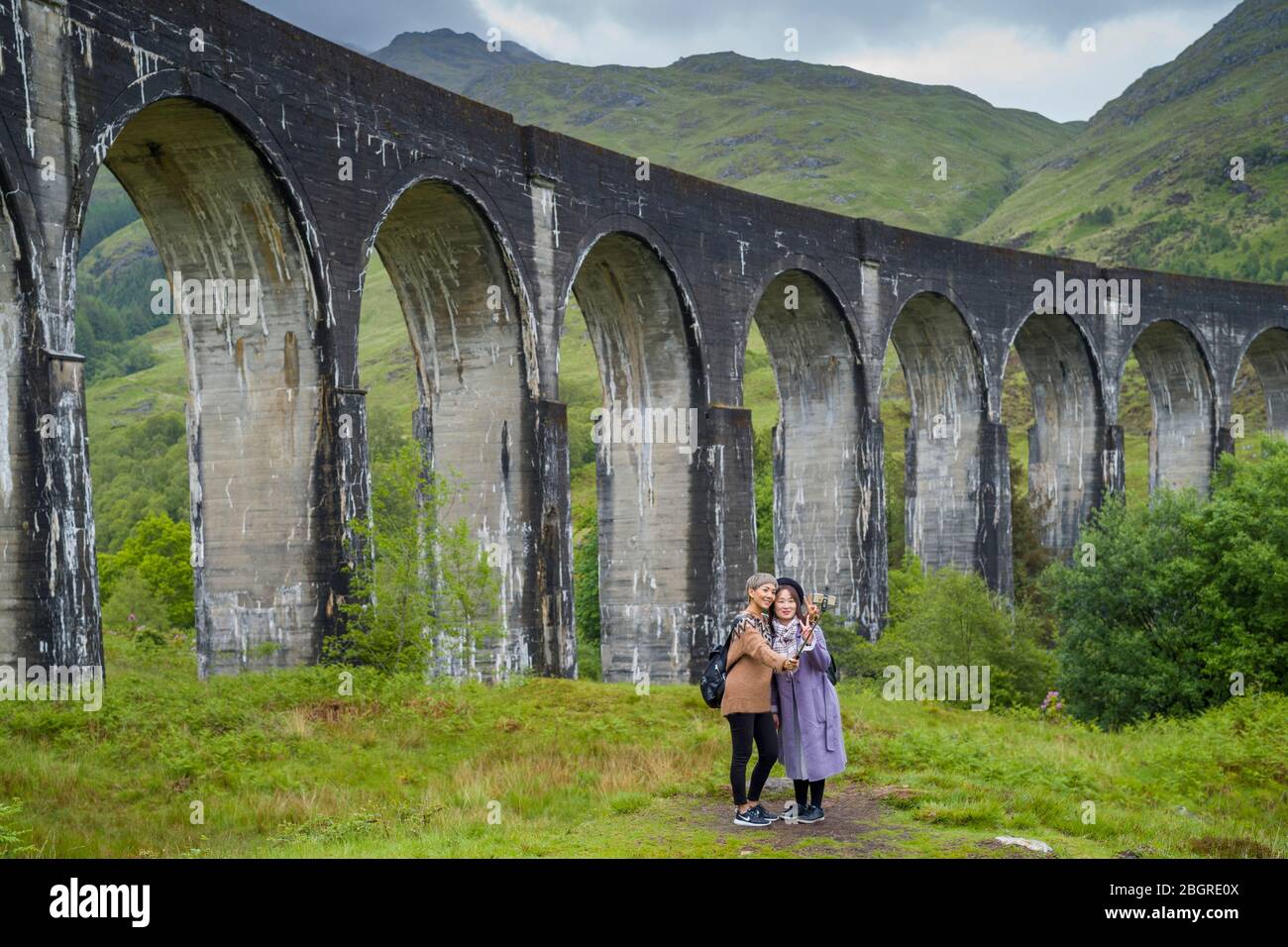 Turisti in posa per selfie nel famoso punto turistico Glenfinnan Viaduct nelle Highlands della Scozia Foto Stock