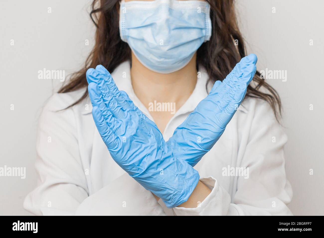 Stop SARS-cov, SARSCoV, virus 2020 , virus cinese COVID-19. Le mani delle donne nei guanti medici blu mostrano il segno DI ARRESTO alla malattia. Medico che indossa la protezione Foto Stock
