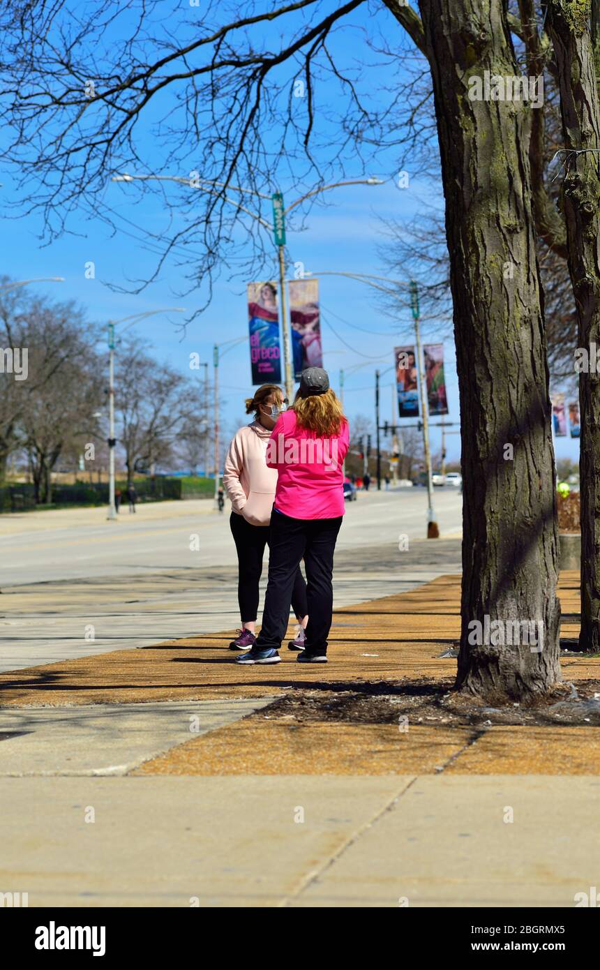Chicago, Illinois, Stati Uniti. Due donne, una con maschera facciale, conversano nel Grant Park, ma non mantengono il requisito di distanza sociale. Foto Stock Chicago, Illinois, Stati Uniti. Due donne, una con maschera facciale, conversano nel Grant Park, ma non mantengono il requisito di distanza sociale. Foto Stock