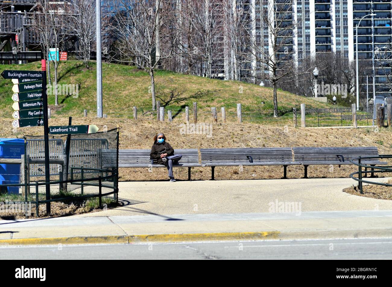 Chicago, Illinois, Stati Uniti. Una donna solita che indossa una maschera facciale poggia su una panchina nel Maggie Daley Park nonostante il parco sia chiuso al pubblico. Foto Stock