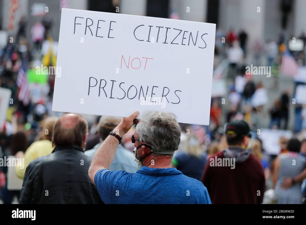 Un uomo che indossa una maschera sostiene un detto "libera cittadini non prigionieri" per una protesta contro le restrizioni di soggiorno a casa durante la pandemia COVID-19 al W Foto Stock