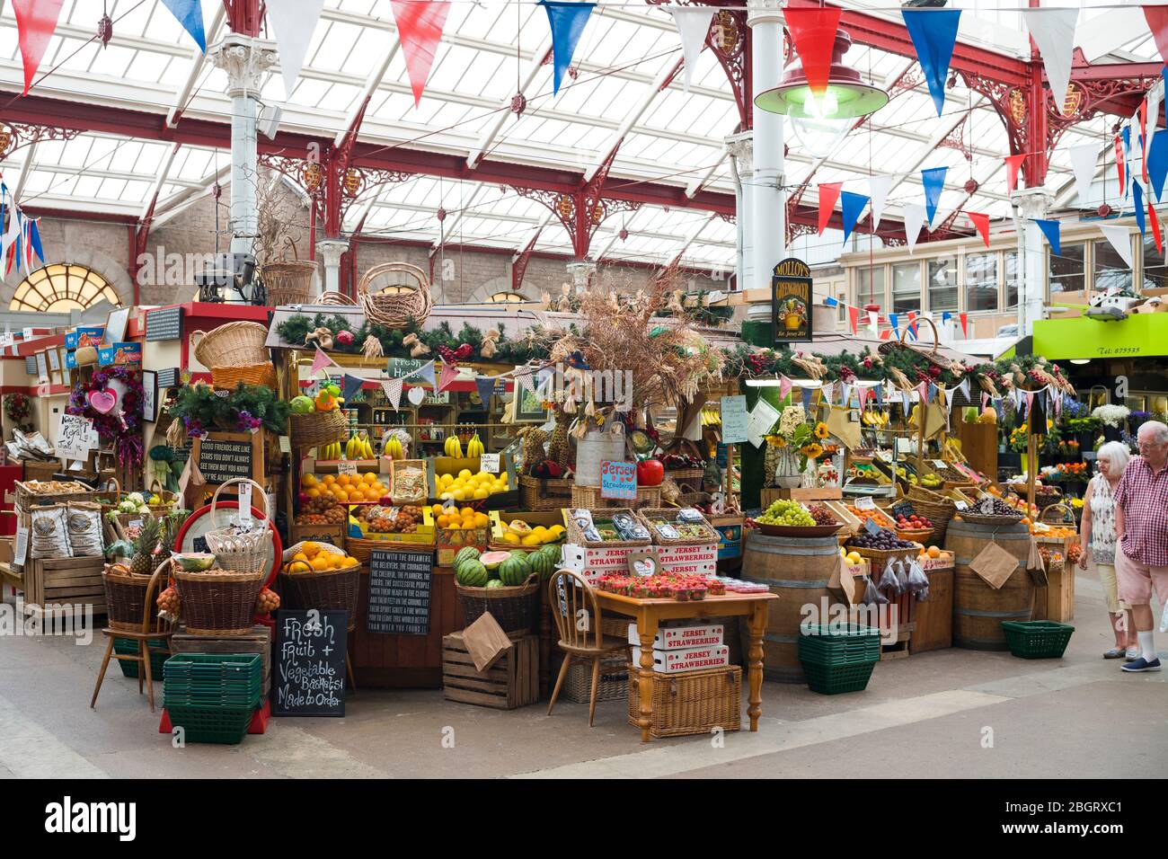 Frutta e altri articoli in vendita al mercato centrale di St Helier nella storica sala del mercato vittoriano, a Jersey, Channel Isles Foto Stock