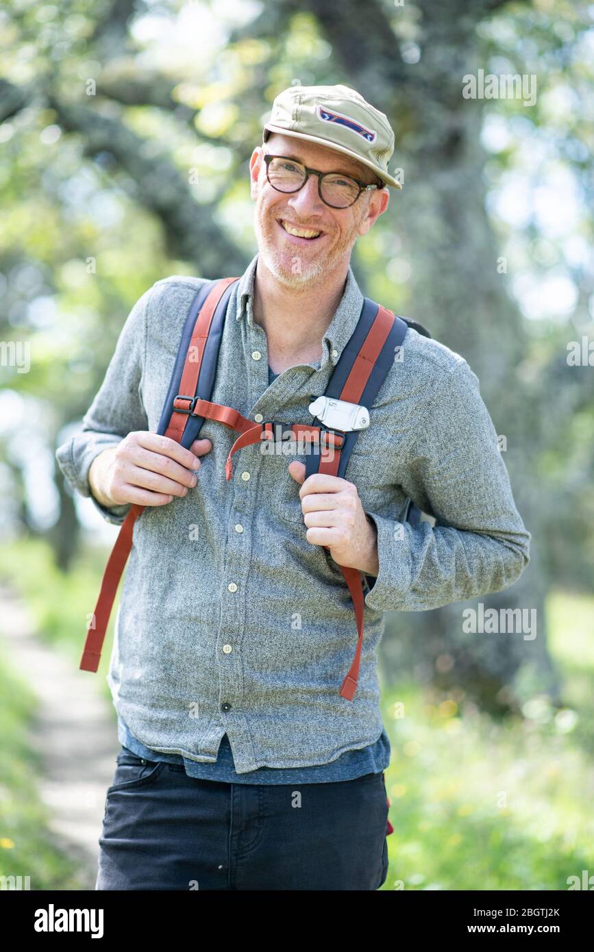 Ritratto di sorridente escursionista con cappello, occhiali e zaino all'aperto Foto Stock