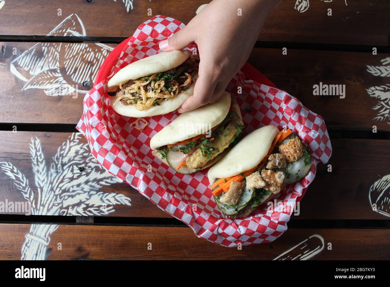 Tre Bao mun su tavolo rustico con mano in su Foto Stock