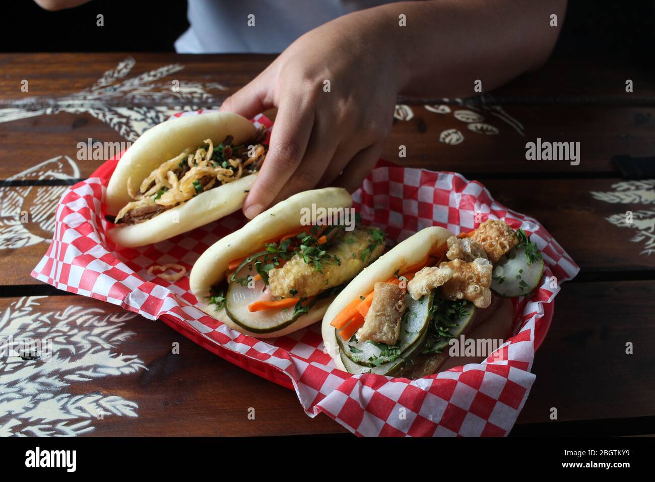 Tre Bao muso su tavolo rustico con una mano Foto Stock