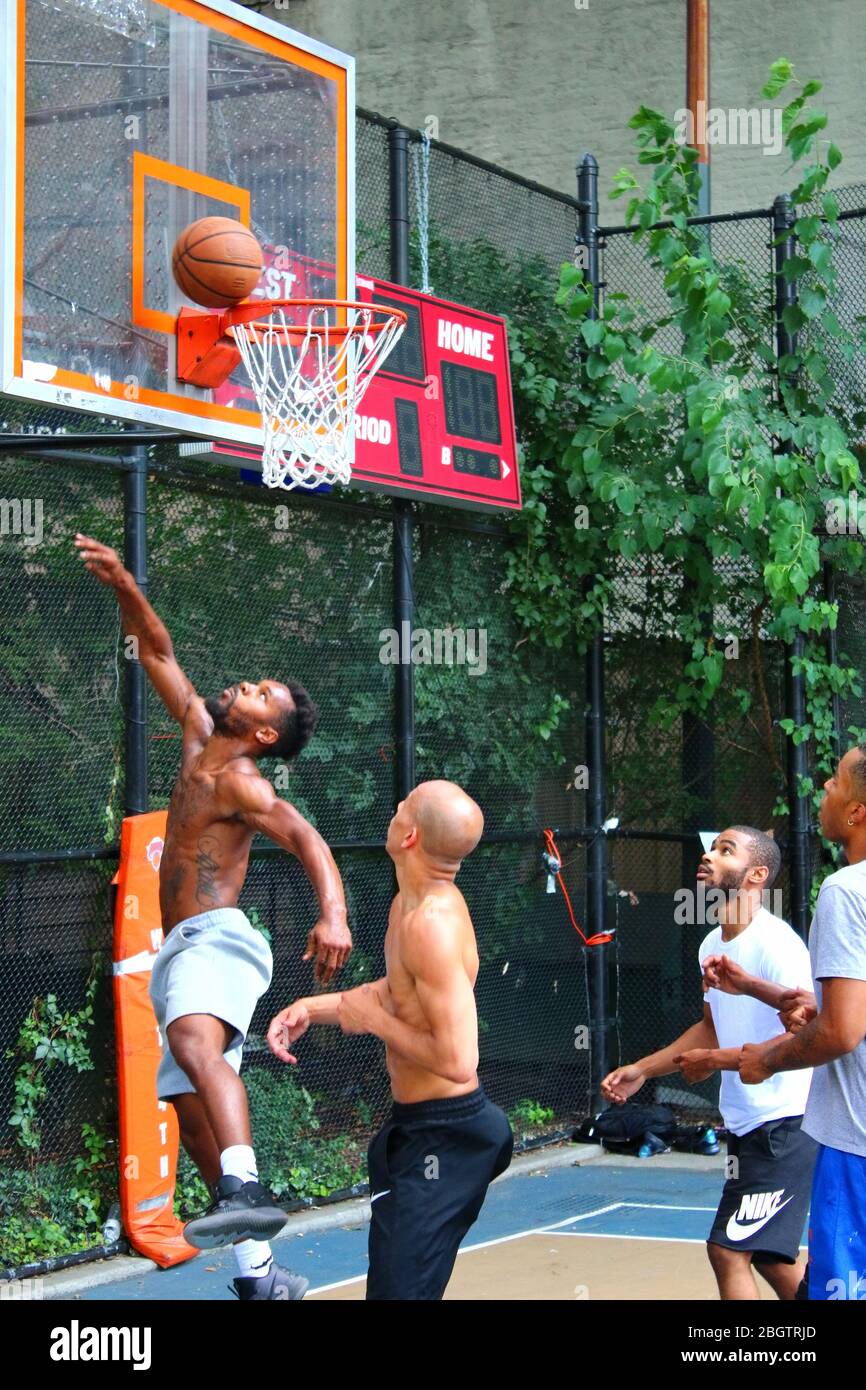 Giocatori dilettanti che si scrambling per la palla sotto il tabellone mentre giocano a basket in 'The Cage', West 4th Street Courts, Manhattan il 29 LUGLIO 2019 i Foto Stock