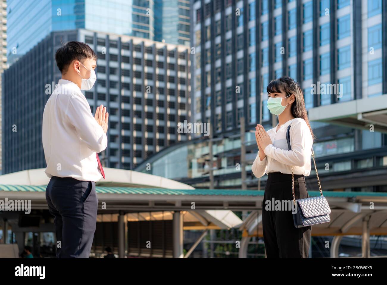 Il rispetto di paga è nuovo saluto del romanzo per evitare la diffusione del coronavirus. Due giovani imprenditori asiatici e imprenditrici si incontrano in fonte di ufficio. Invece di Foto Stock