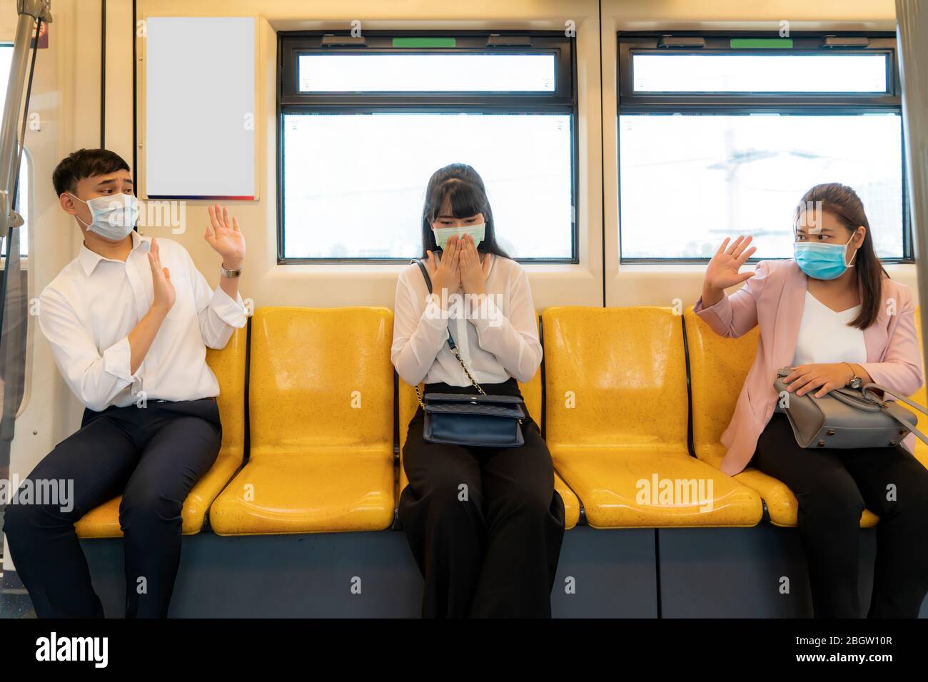 Donna asiatica d'affari che indossa maschera starnuti o tossire in metropolitana e altre persone stop segno mano per mantenere la distanza proteggere da virus COVID-19 e pe Foto Stock