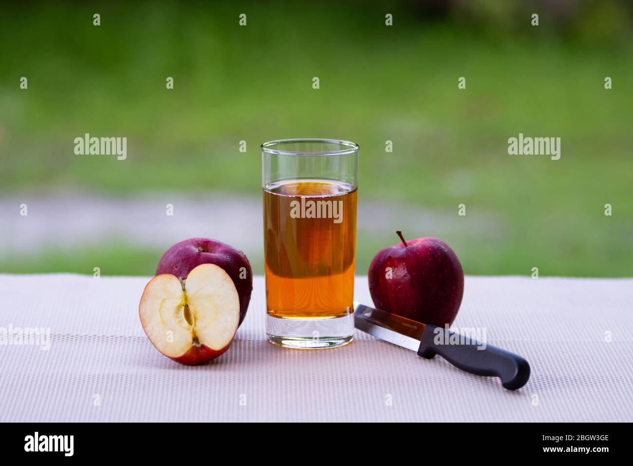 Un bicchiere di succo di mela sano e frutti di mela rossi. Foto Stock