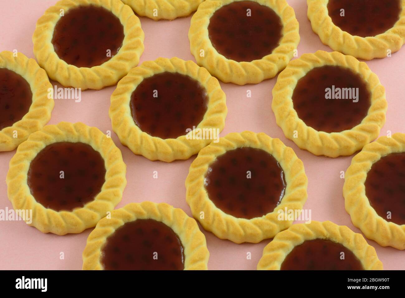 Primo piano di biscotti rossi di tartlette di frutta lampone su sfondo rosa Foto Stock