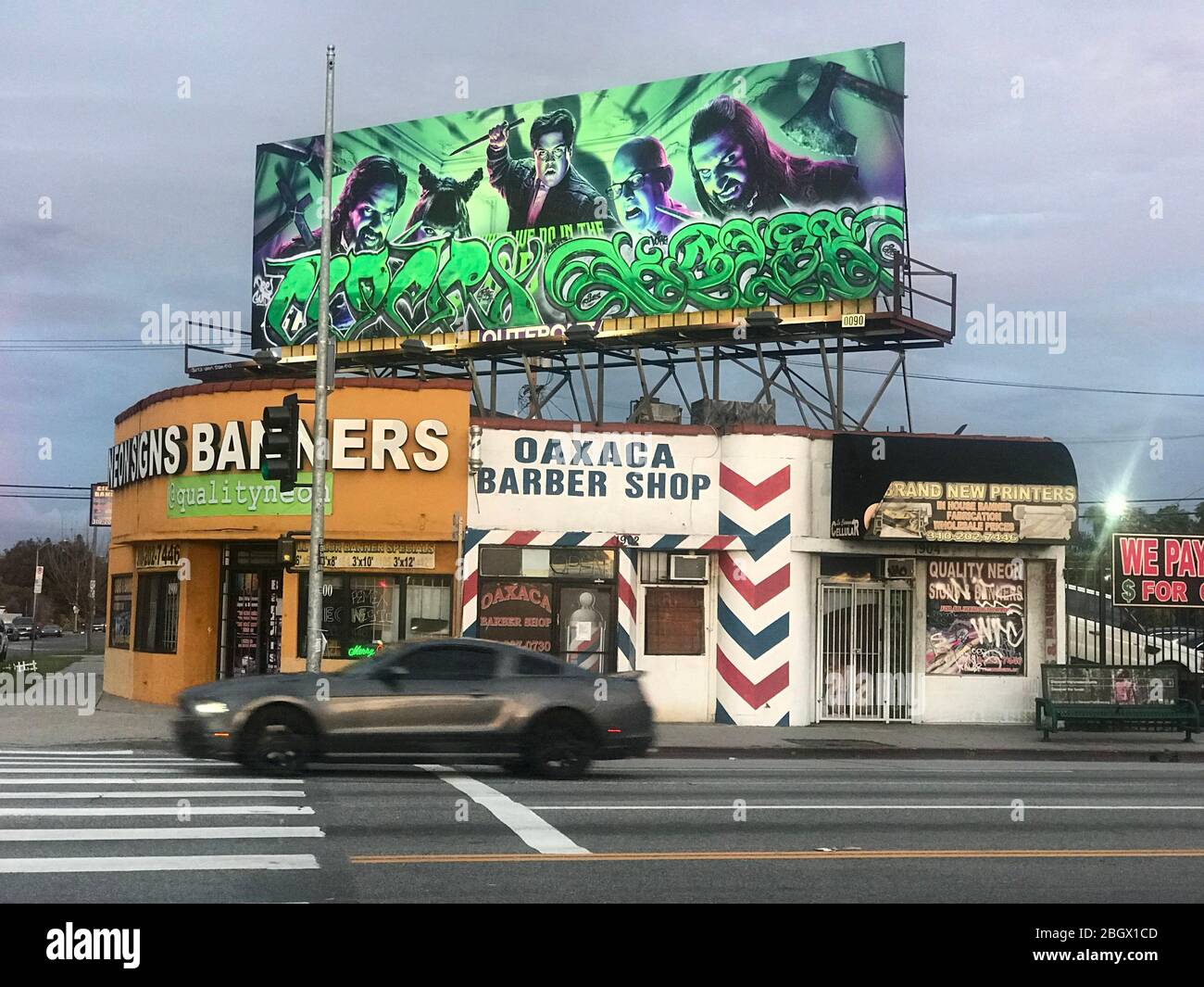 Negozi ad angolo su la Cienega Blvd. A Los Angeles con un negozio di cartelli e banner, un barbiere messicano e un tabellone con graffiti a Los Angeles, California Foto Stock