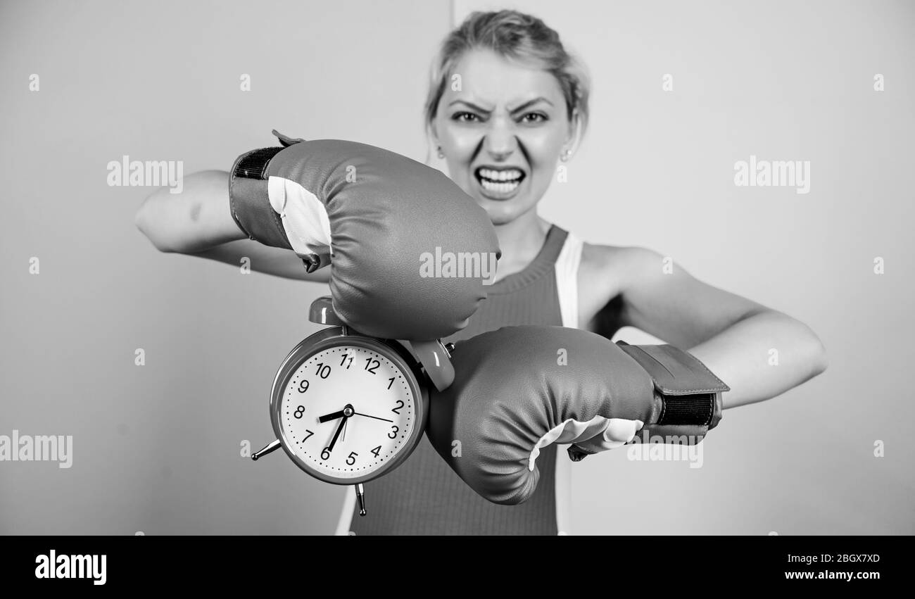 Sportive. vincere il giorno. arrabbiato donna guantoni da pugilato. ragazza boxer tenere premuto il tasto alarm clock. Mattina energia. pieno di potenza. tempo di attività. Che stabilisce il tempo di clock. Il momento di combattere. Il tempo necessario per il successo. Foto Stock