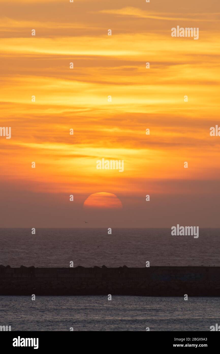 Tramonto sulla spiaggia di Essaouira Marocco vicino all'orizzonte con le onde Foto Stock