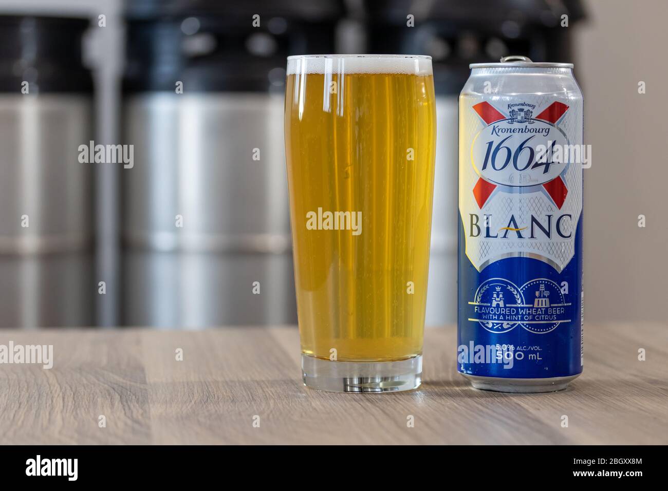 La birra Kronenbourg 1664 Blanc può essere servita su un tavolo accanto a un bicchiere pieno di birra con fusti impilati sullo sfondo Foto Stock