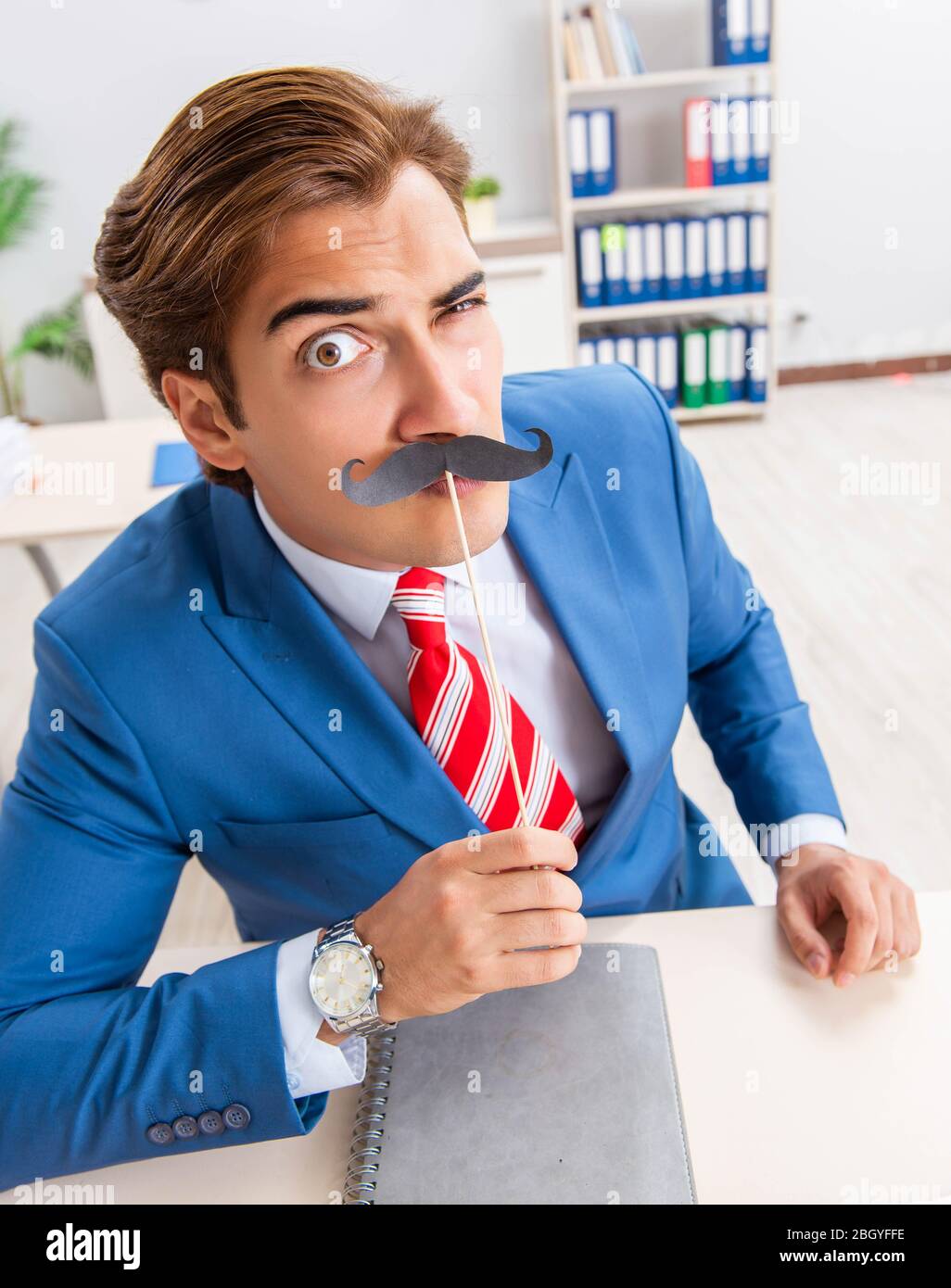 La divertente bisinessman con baffi finti in ufficio Foto Stock