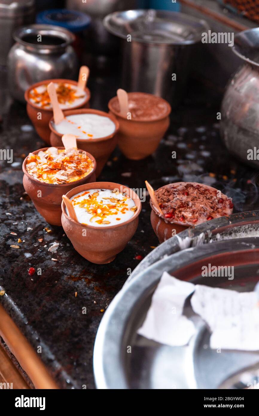 Bevanda popolare indiana Lassi (tradizionale bevanda a base di yogurt Dahi) in tazza di argilla con varie cimate sulla strada a Varanasi. Foto Stock