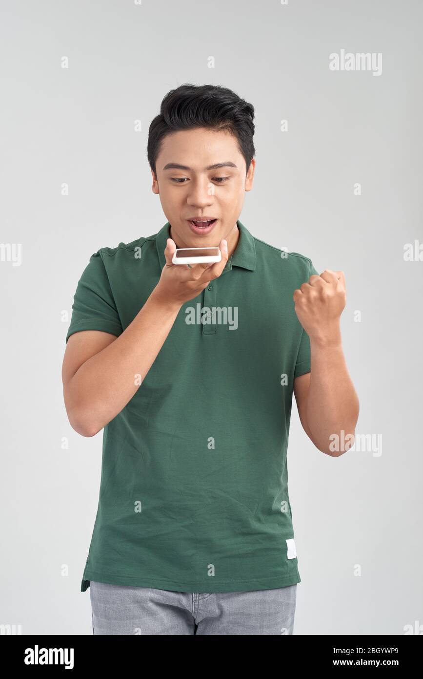 Buon uomo che usa il riconoscimento vocale sul cellulare per inviare un messaggio registrato Foto Stock