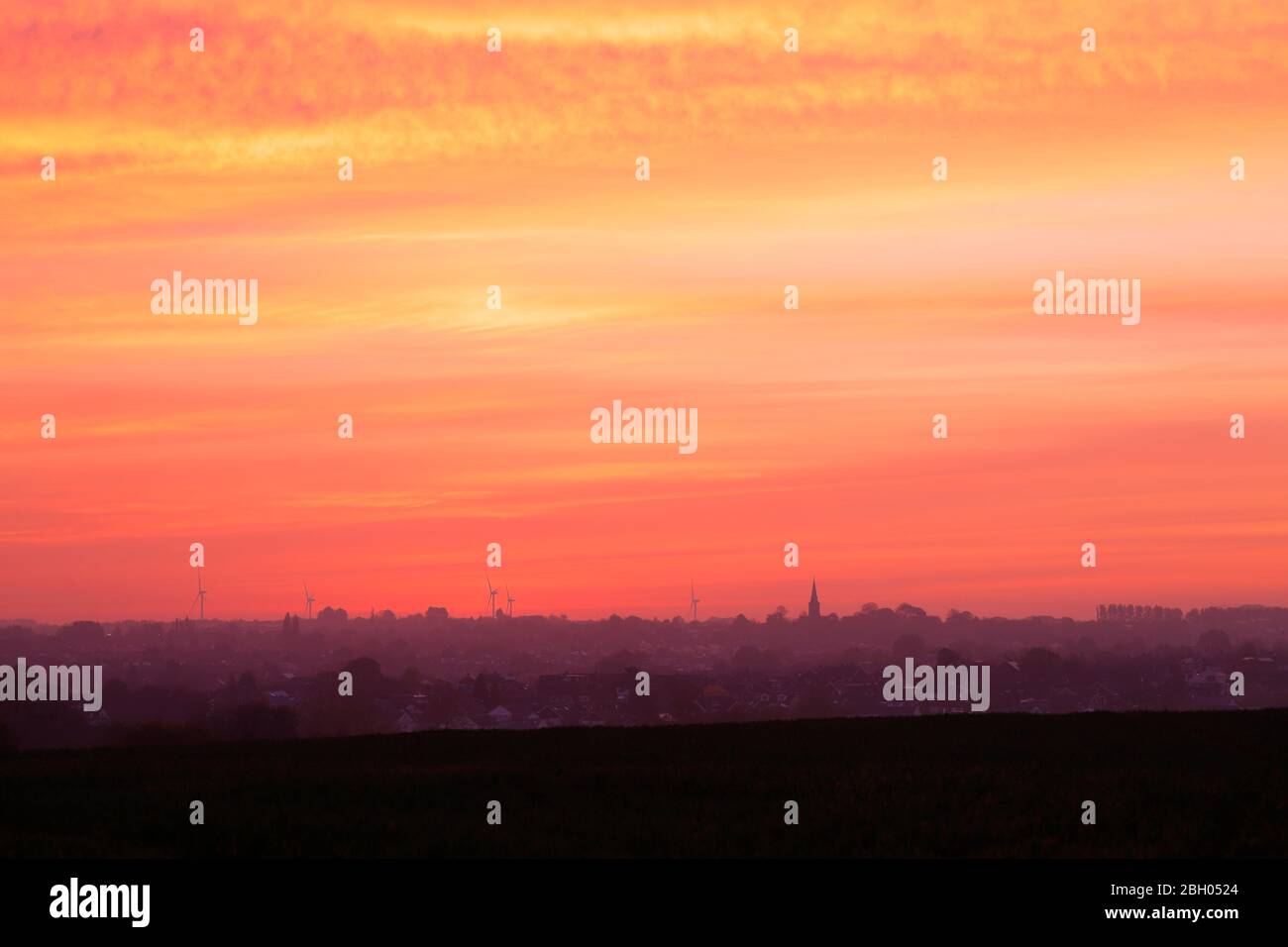 Una bella alba su Garforth a Leeds. Hook Moor Wind Farm & St Mary's Church si distinguono sopra l'orizzonte Foto Stock