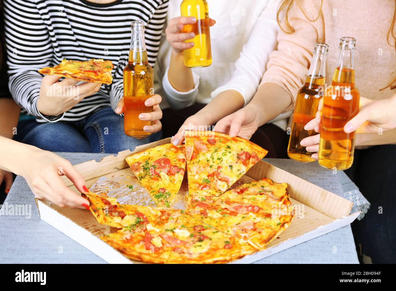 Gli amici si avvicinano a bottiglie di birra e pizza Foto stock - Alamy