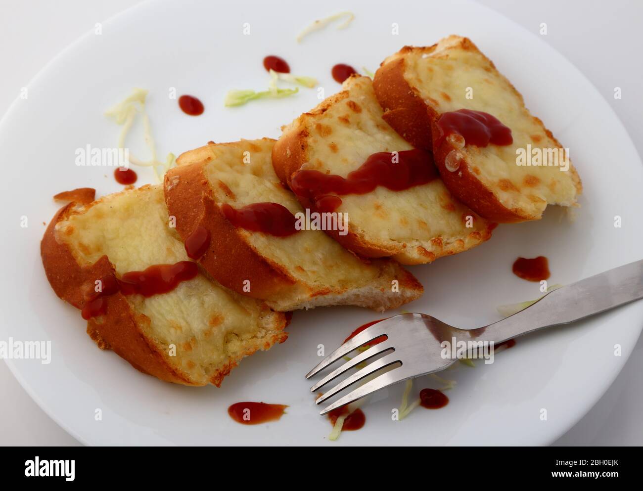 Fette di pane all'aglio e alle erbe con salsa di pomodoro in piatto bianco. Foto Stock