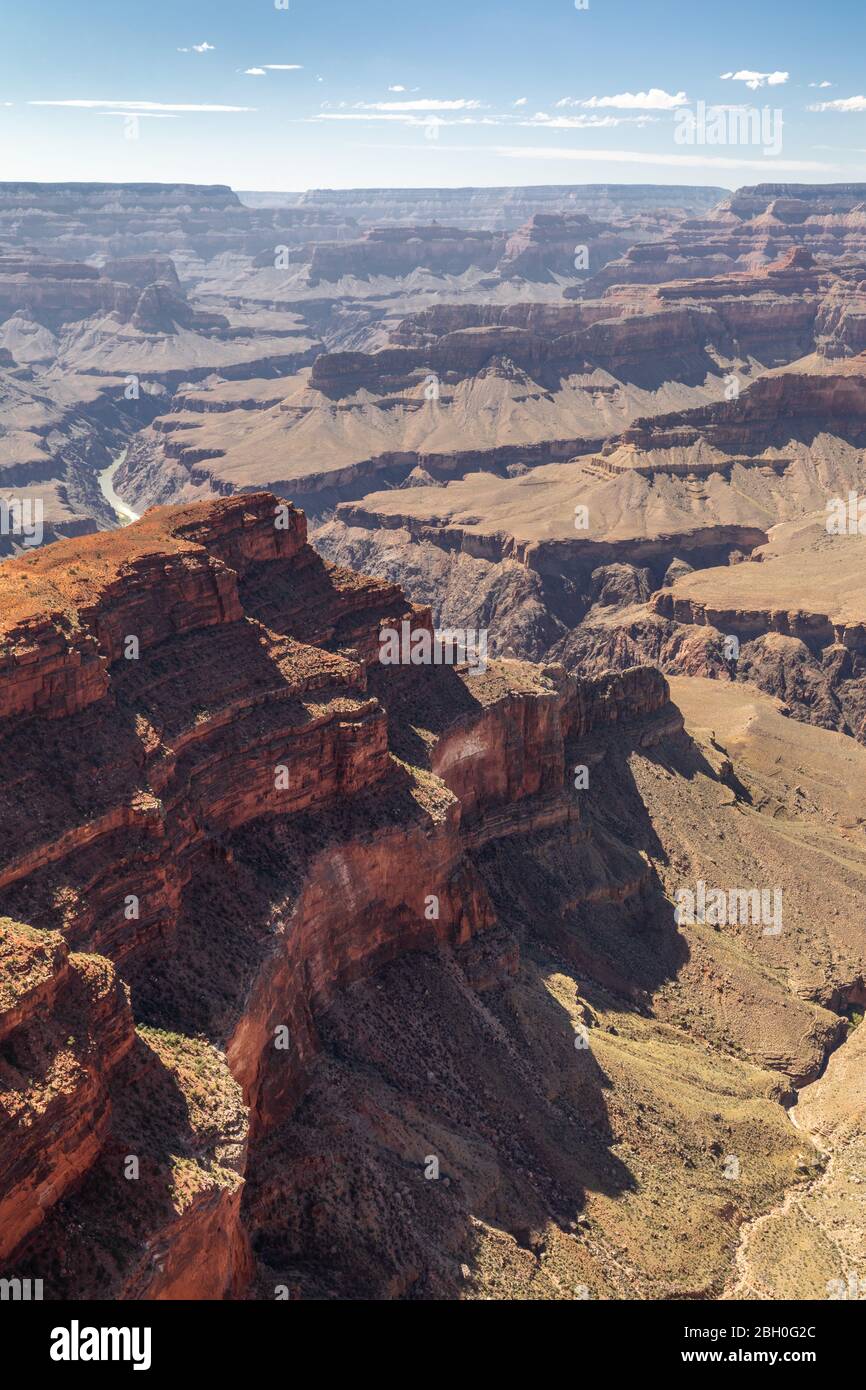 Vista grandangolare del Grand Canyon visto da un punto di vista, con una grande mesa arancione in primo piano, sotto un cielo blu con nuvole sparse Foto Stock