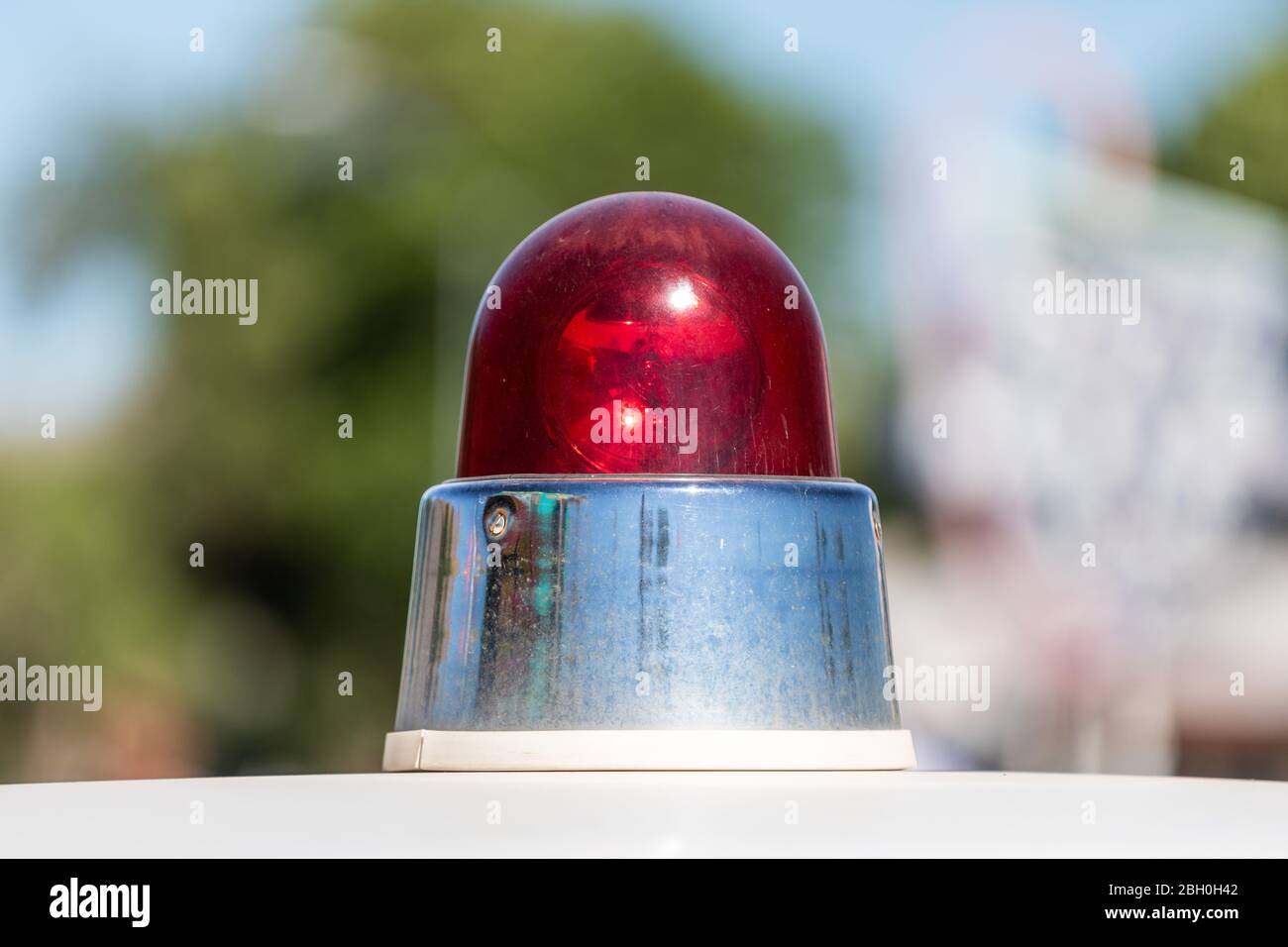 Primo piano di una sirena rossa d'epoca americana della polizia, contro uno sfondo verde bokeh Foto Stock