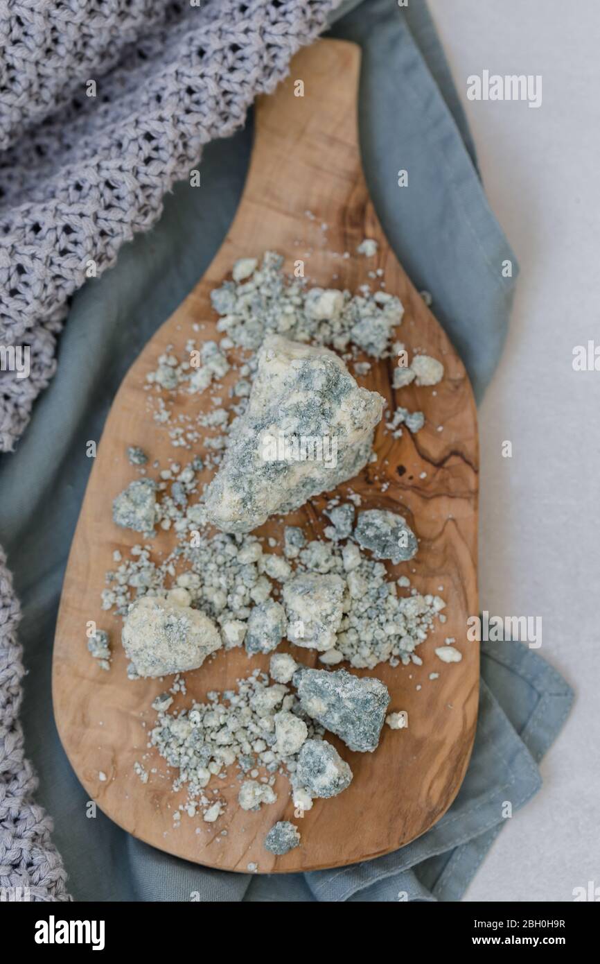 Immagine della vista superiore del formaggio turco tulum servito sul bordo di legno posto sul colore turchese e sul piano del tavolo grigio chiaro Foto Stock