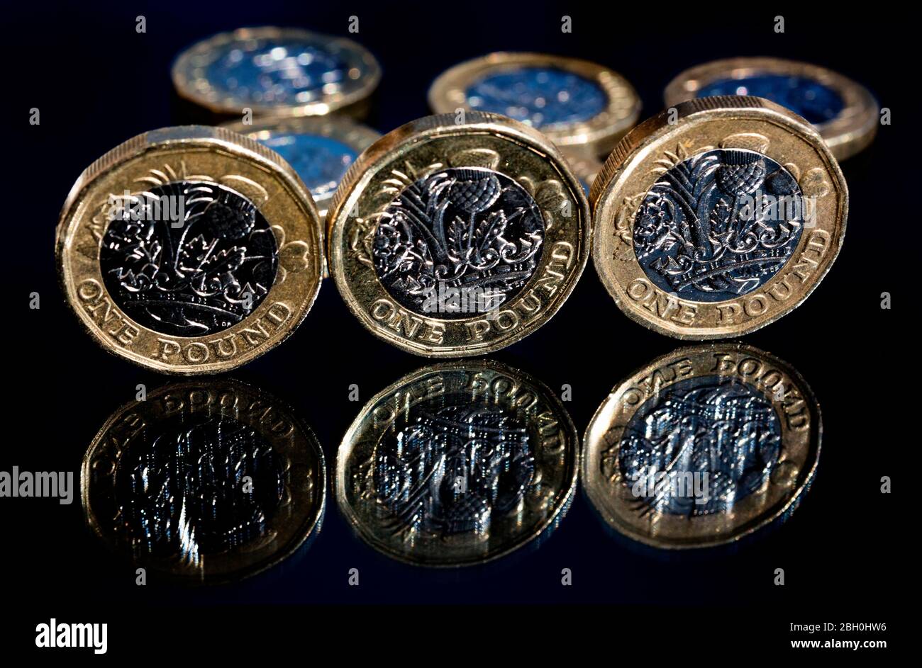 3 monete inglesi da una libbra riflesse su una superficie di vetro Foto Stock