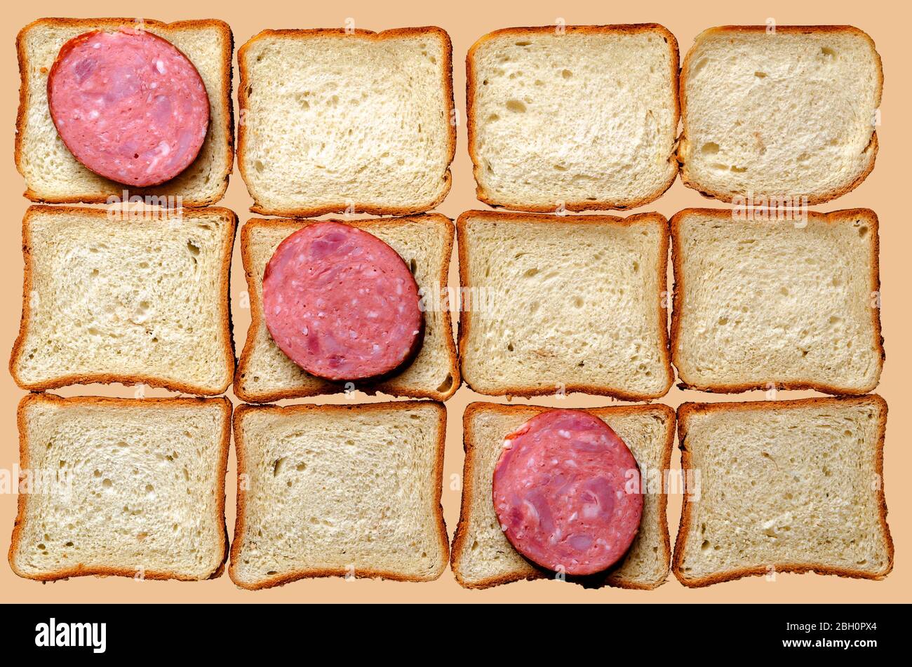Tre fette di salame e pane per panini. Dodici pezzi di pane e salsiccia affumicata su sfondo beige chiaro. Vista dall'alto. Foto Stock