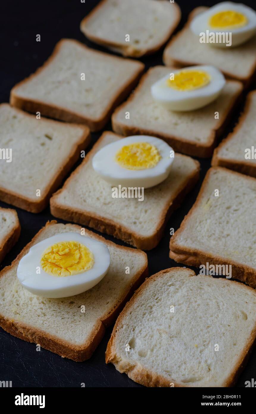 Uova sode a metà e pane tostato. Quattro pezzi di uova di pollo sul pane. Background creativo in una prospettiva di receding. Focus nel foregroun Foto Stock