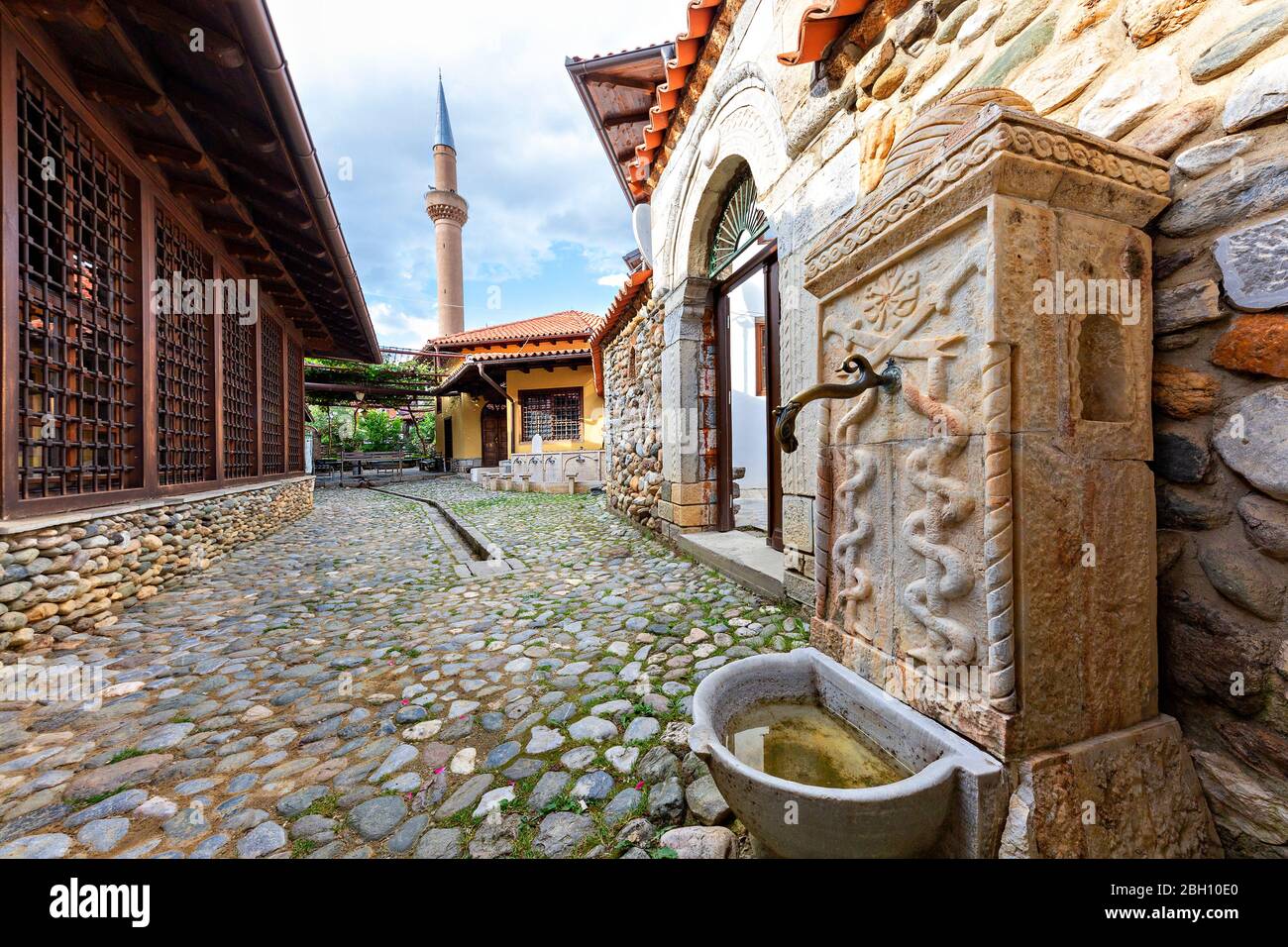 Antica fontana con il minareto della Moschea Tekke di Halveti sullo sfondo, Prizren, Kosovo Foto Stock