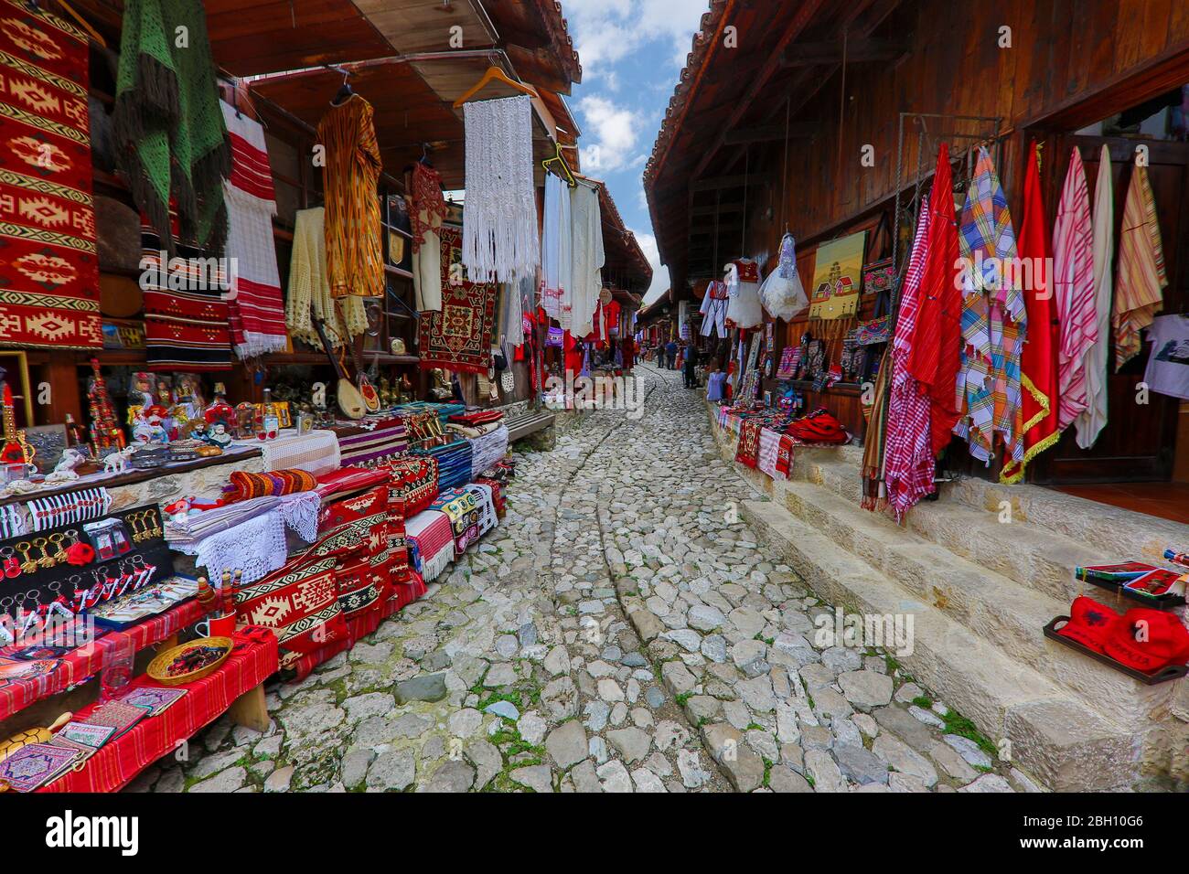 Negozi di tessili in strada acciottolata nella città vecchia di Kruje, Albania Foto Stock