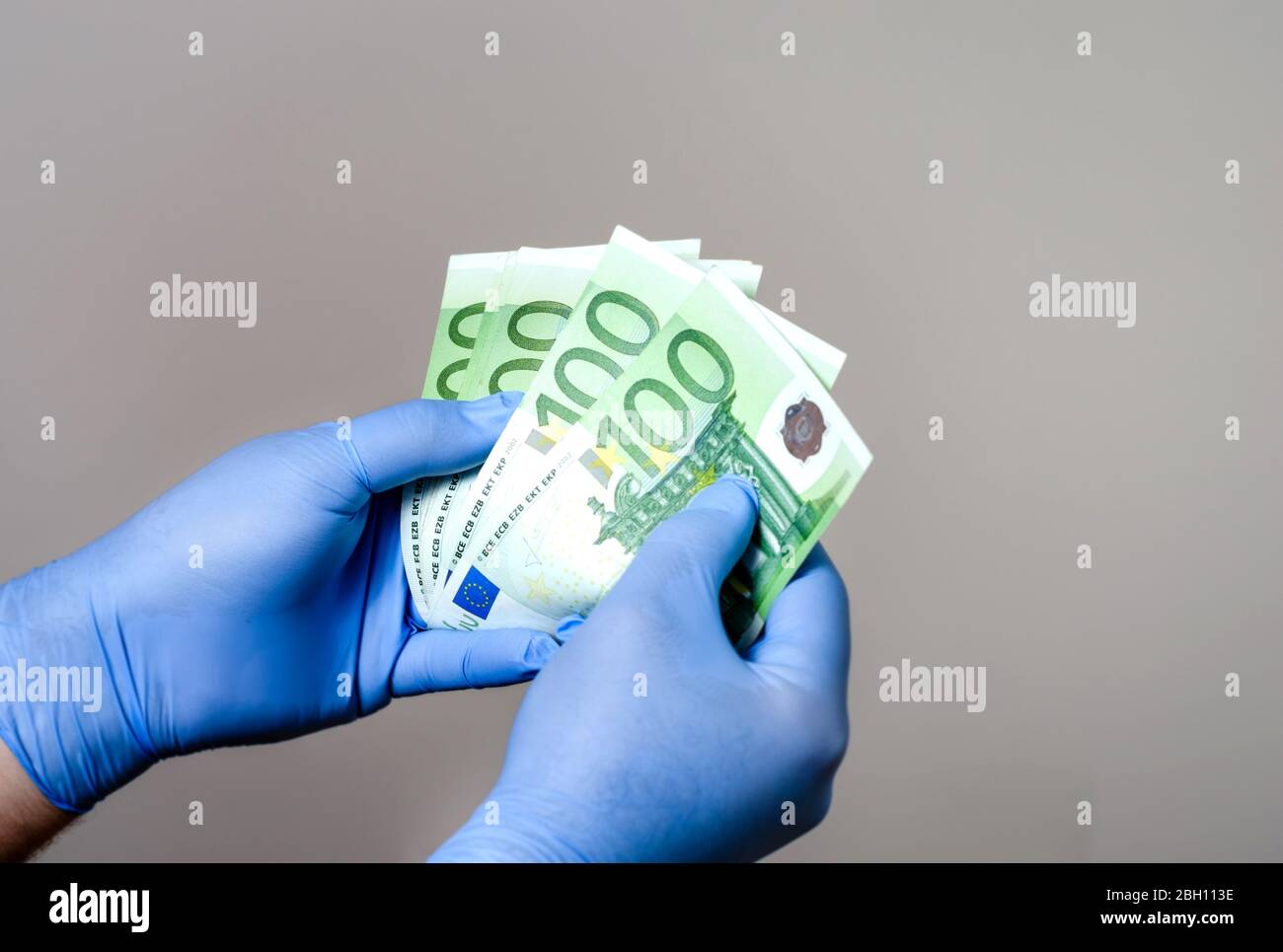 Uomo con guanti chirurgici in mano contando gli euro bancknotes .protezione contro la contaminazione con covid-19 e battery.UE economia durante Foto Stock