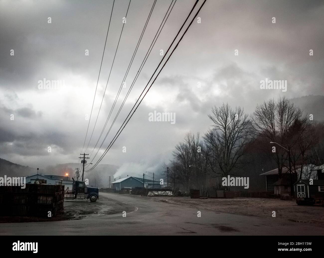 Linee elettriche e un camion si trovano su una strada deserta in una città industriale sotto nuvole e nebbia nell'Upstate New York, nella città di Deposit, NY, USA Foto Stock