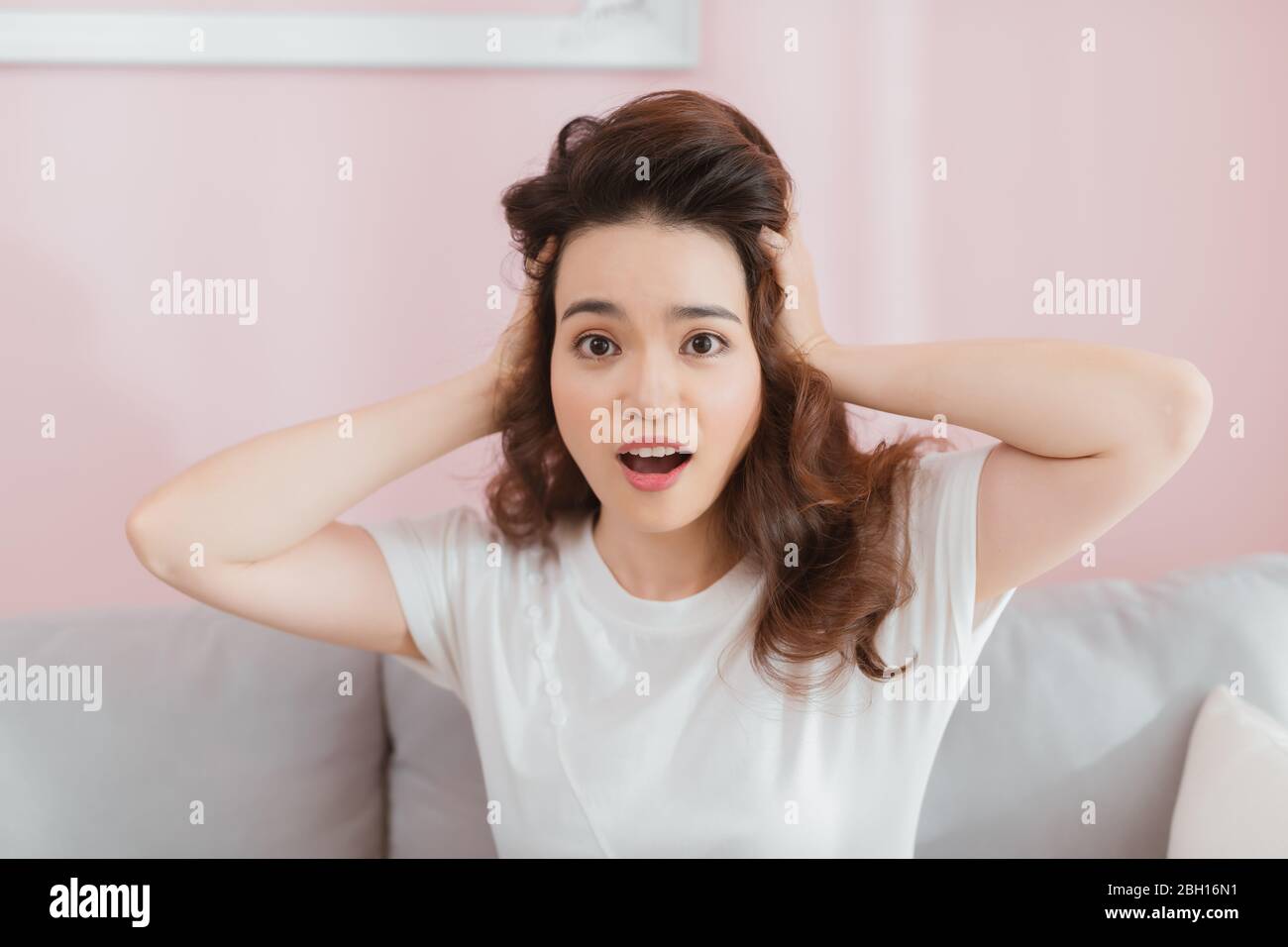 Ritratto di attraente sorpreso eccitato spaventato teenage urlante, tiene le mani sulla testa, bocca aperta sul soggiorno. Concetto di studente preoccupato, giovane pr Foto Stock