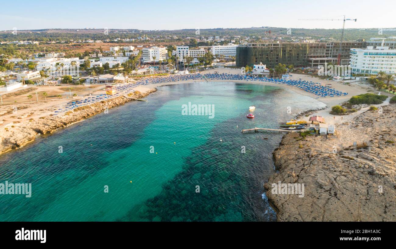 Vista aerea dall'alto della spiaggia di Vathia Gonia, Ayia Napa, Famagosta, Cipro. L'attrazione turistica punto di riferimento baia rocciosa all'alba con sabbia dorata, sole Foto Stock