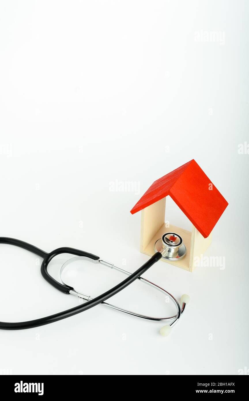Concetto di medicina di famiglia - Casa rossa Mini e stetoscopio isolato su sfondo bianco Foto Stock