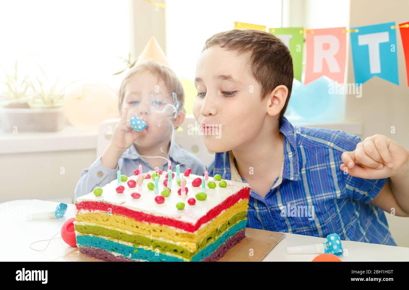 I bambini che festeggiano il compleanno e che soffiano le candele sulla torta sono bellissimi Foto Stock