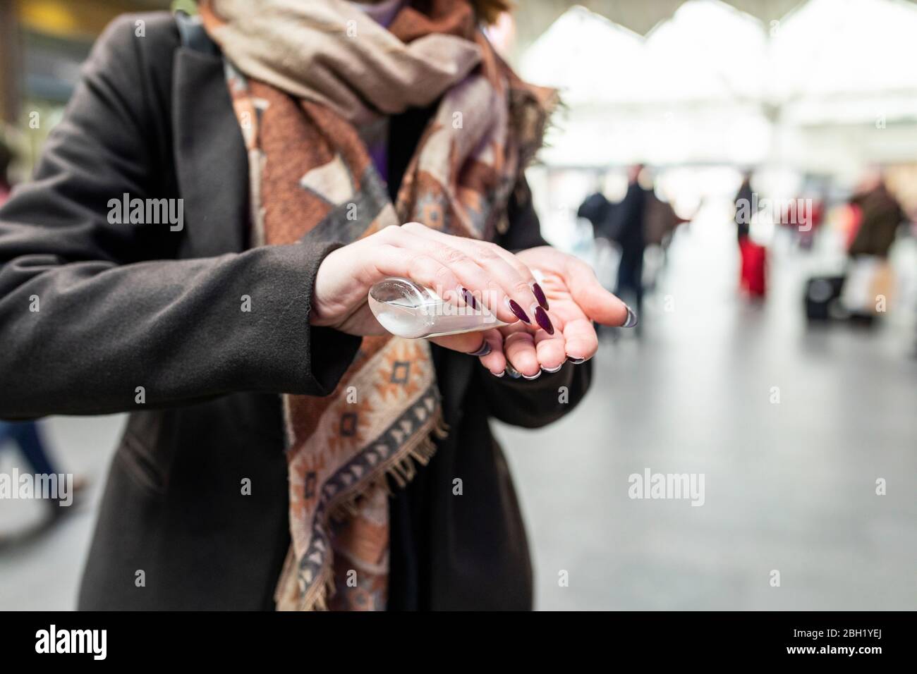 Donna che usa gel disinfettante per le mani alla stazione ferroviaria Foto Stock