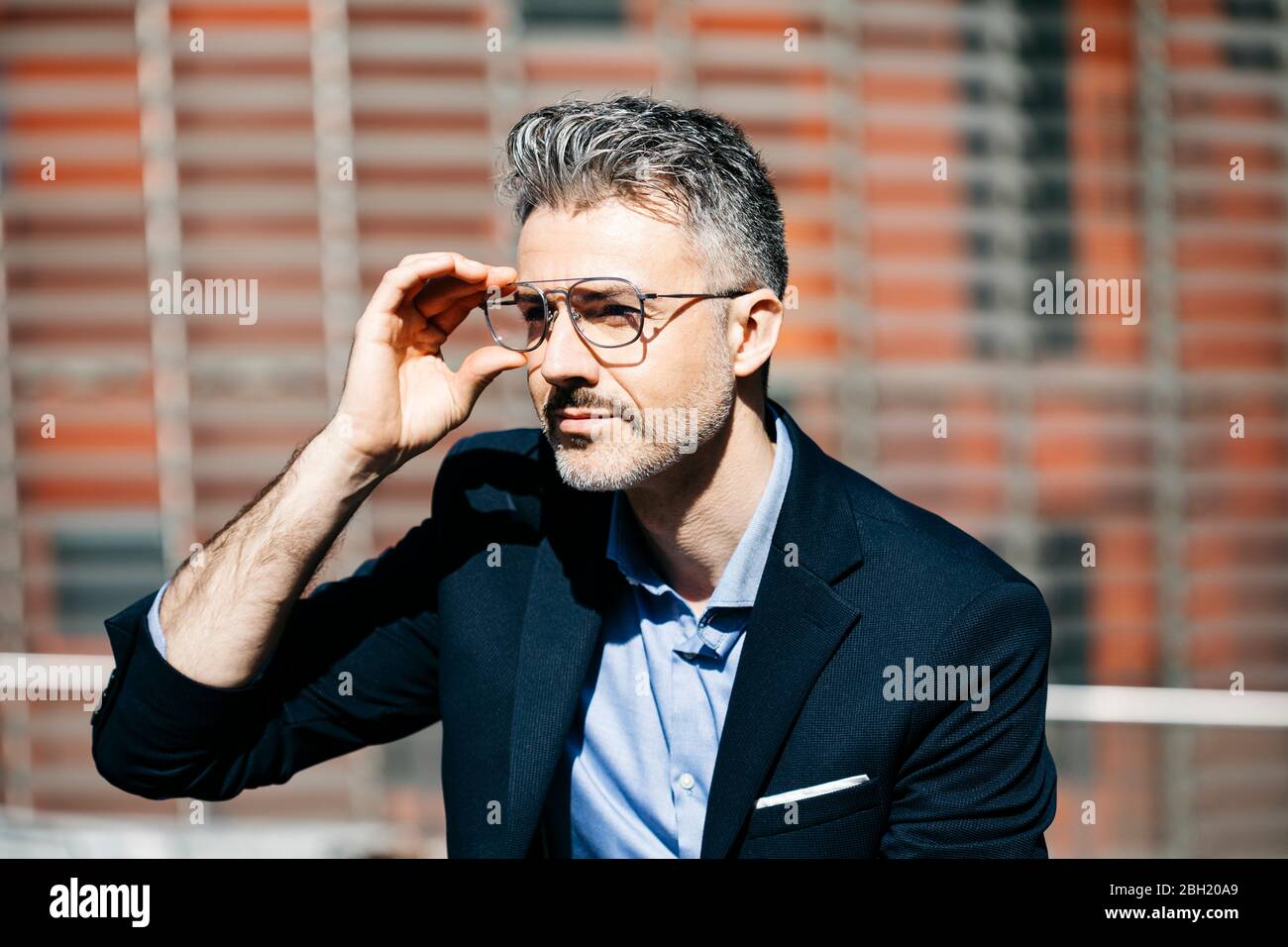 Ritratto di un uomo d'affari con capelli grigi in città che indossa i bicchieri Foto Stock
