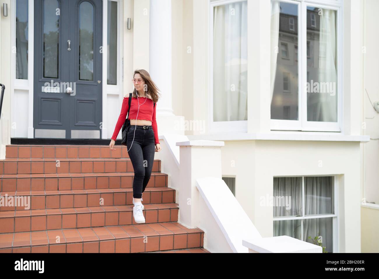 Giovane donna che cammina giù stoop Foto Stock