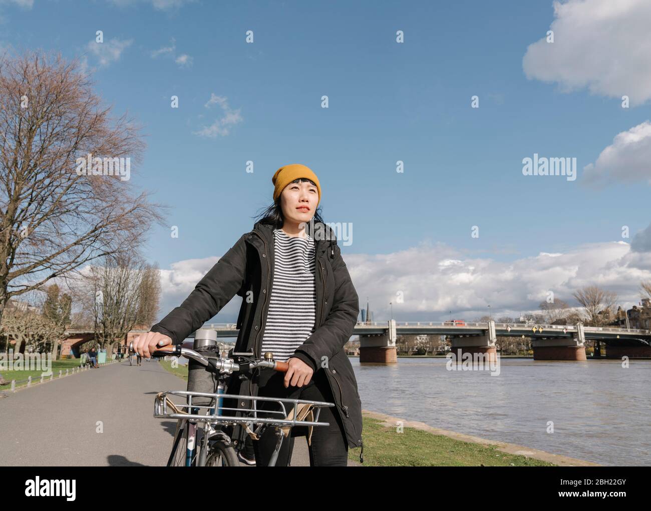 Donna con bicicletta sulla riva del fiume, Francoforte, Germania Foto Stock