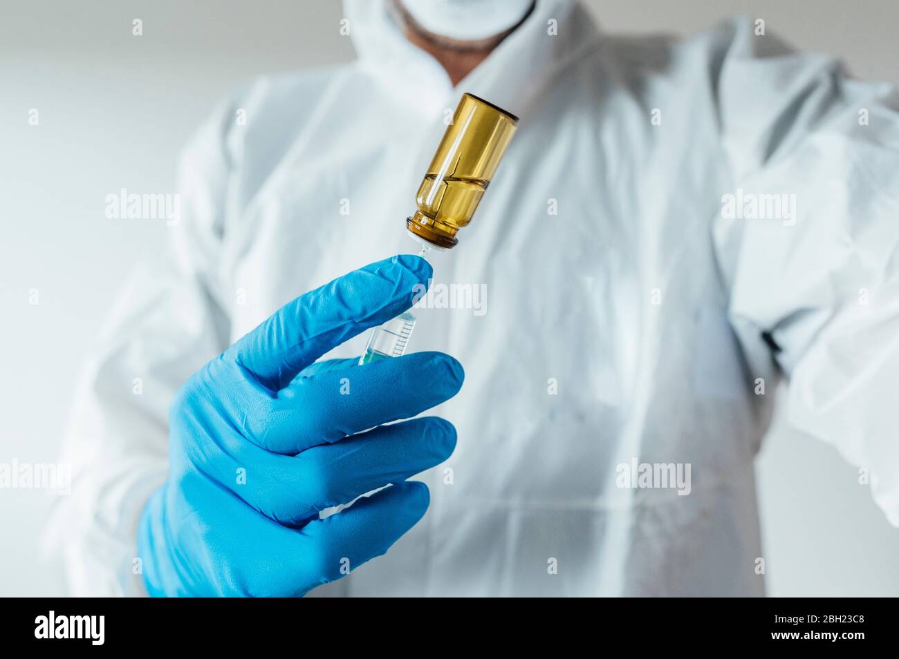 Tecnico di laboratorio che indossa indumenti protettivi, che tiene il vaccino Foto Stock